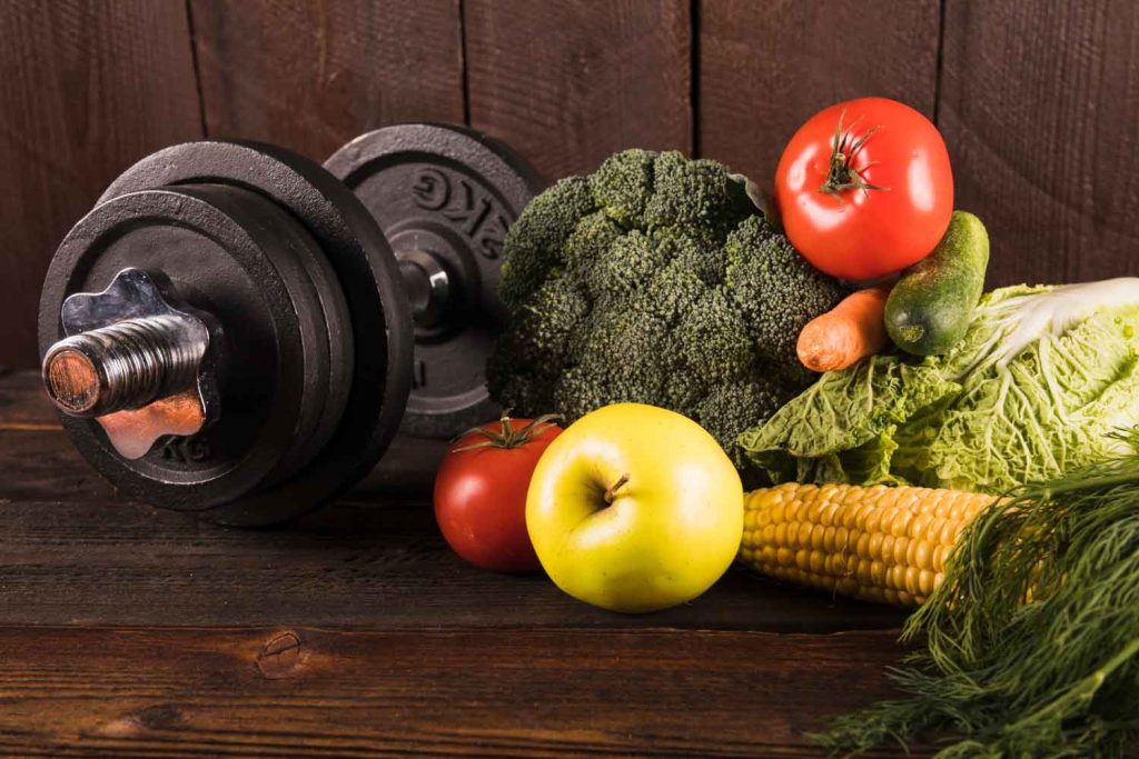 Dumbbells and vegetables representing healthy weight management